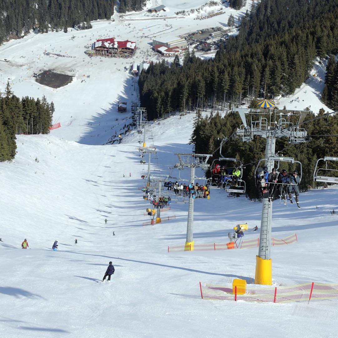 Blick auf die Skipiste: Skifahren und Snowboarden auf der einen Seite, Sessellift auf der anderen