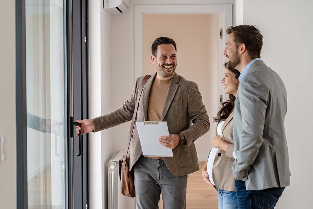 Irische Käufer schließen erfolgreichen Kauf einer bulgarischen Wohnung ab Irische Immobilienkäufer feiern den erfolgreichen Abschluss ihres Wohnungskaufs mit einem bulgarischen Immobilienmakler bei einer letzten Besichtigung eines leeren neuen Hauses